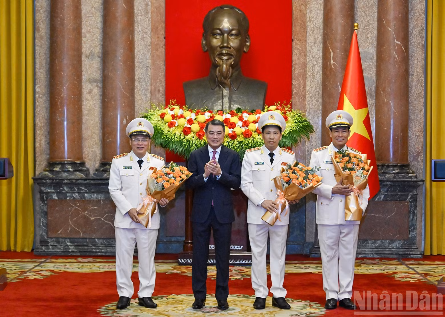 Chaiman of the Party Central Committee’s Organisation Commission Le Minh Hung presents flowers to congratulate Le Tan Toi, Le Van Tuyen, and Nguyen Van Long.