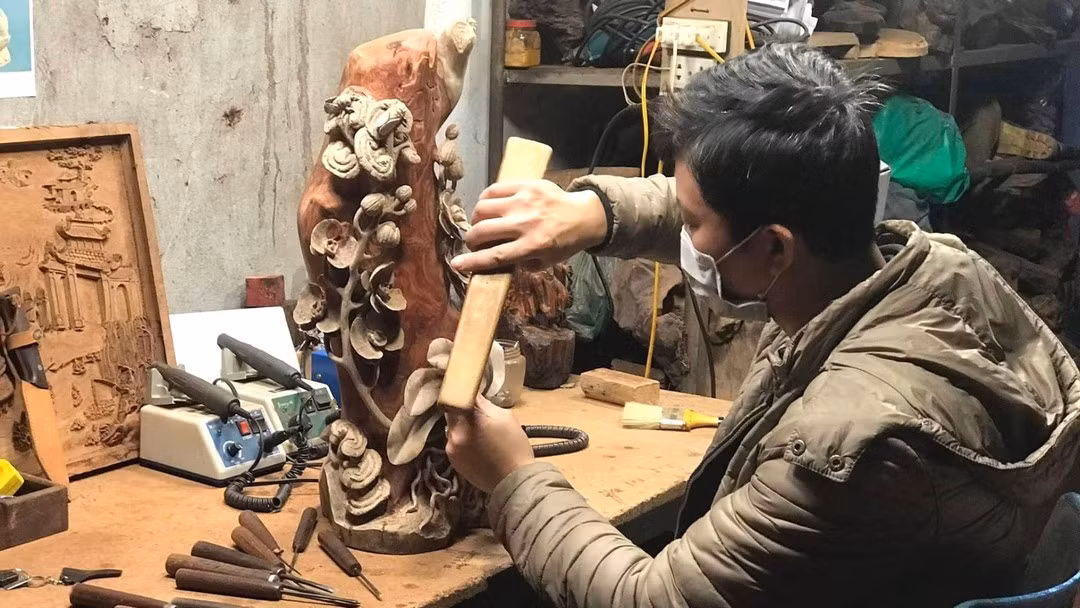 An artisan carefully works on every detail of the carving.