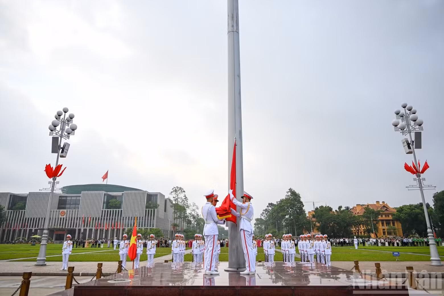 The national flag unit marches solemnly up the steps beneath the flagpole and attaches the flag.